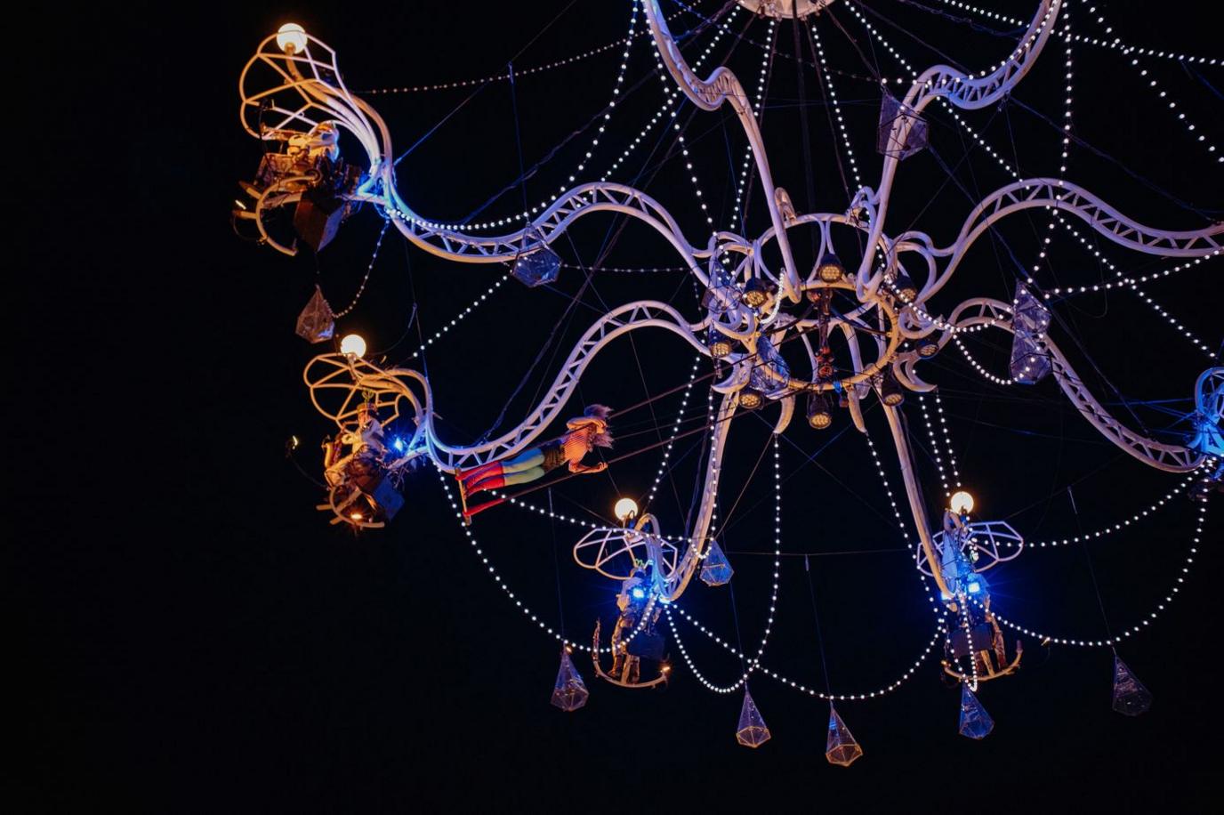 Acrobat swings below chandelier