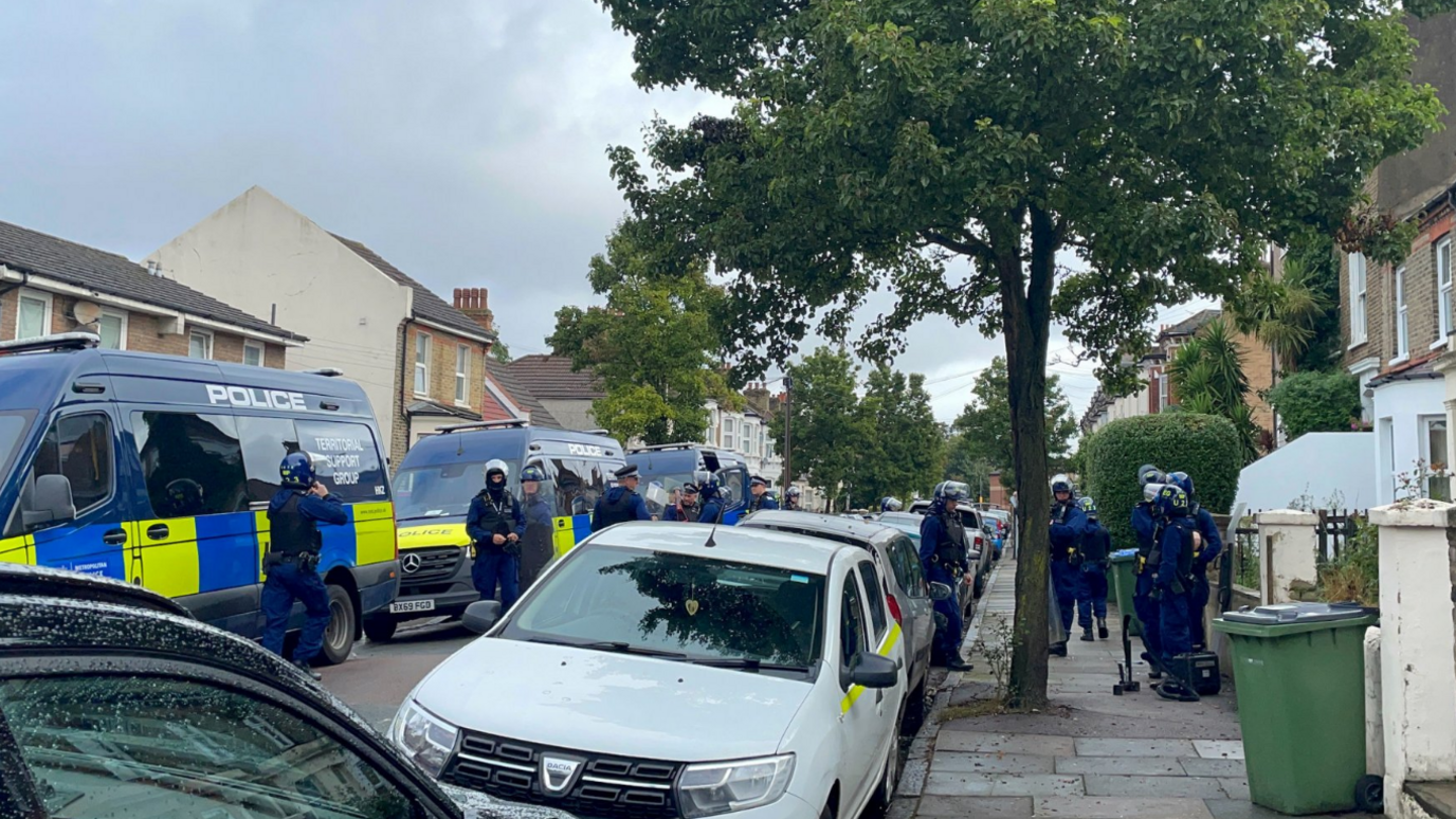 Metropolitan Police Territorial Support Group officers and vans at the scene in Eglinton Road