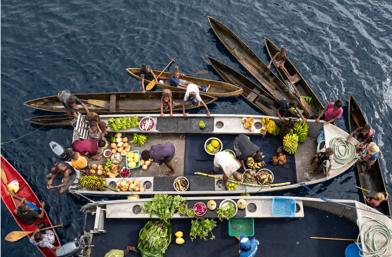 Solomon Islanders come to dive boat to sell fruit and vegetables from their dugout canoes