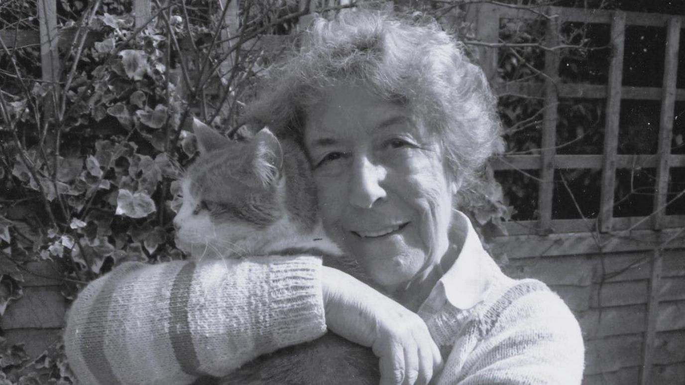 A black and white photograph of an elderly woman holding a cat.