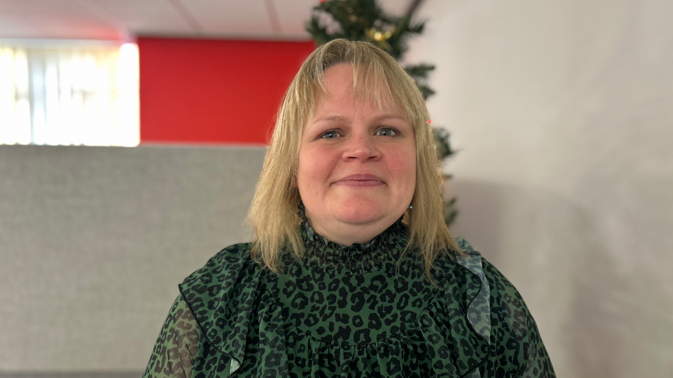 Sian Evans mewn blows patrymog gwyrdd a du.