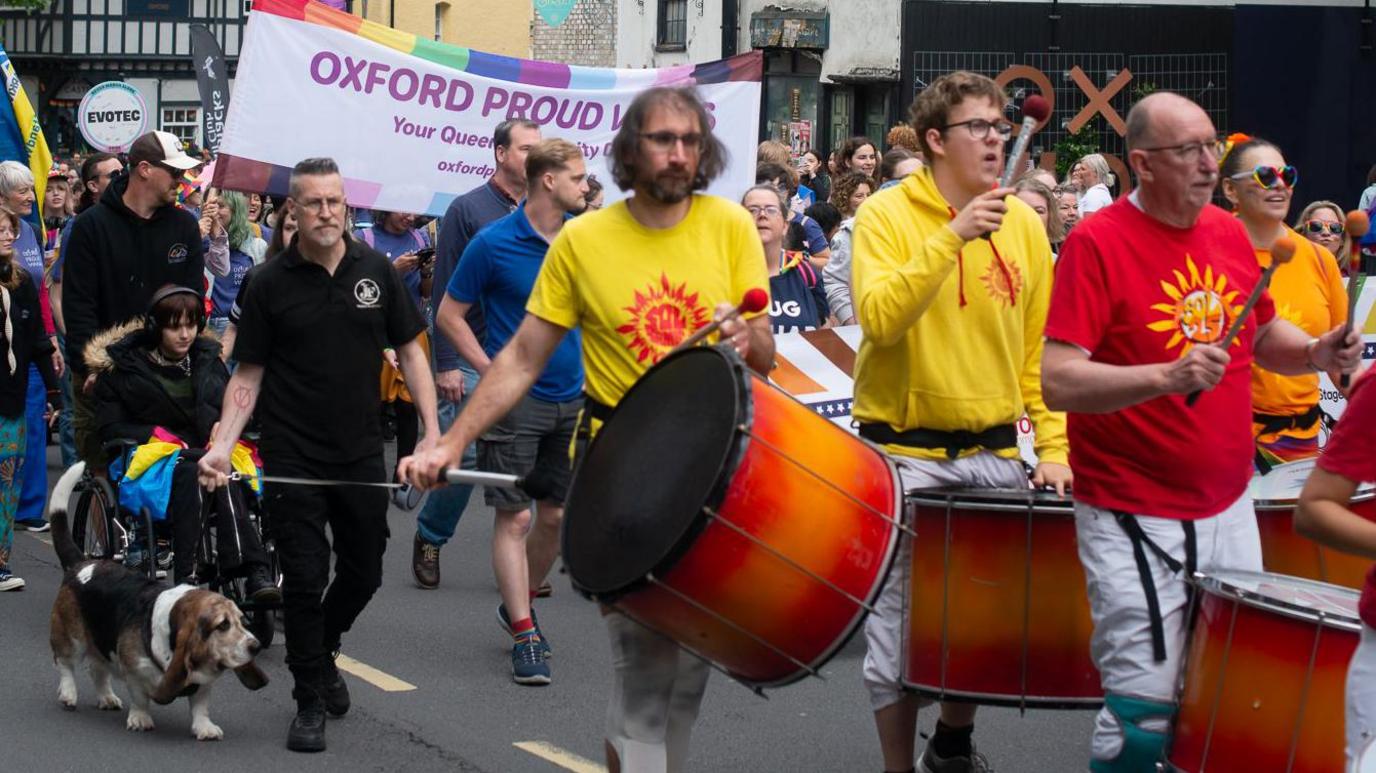 Part of the parade on 7.6.25 includes kettle drummers wearing brightly-coloured T-shirts and marchers with flags and banners.