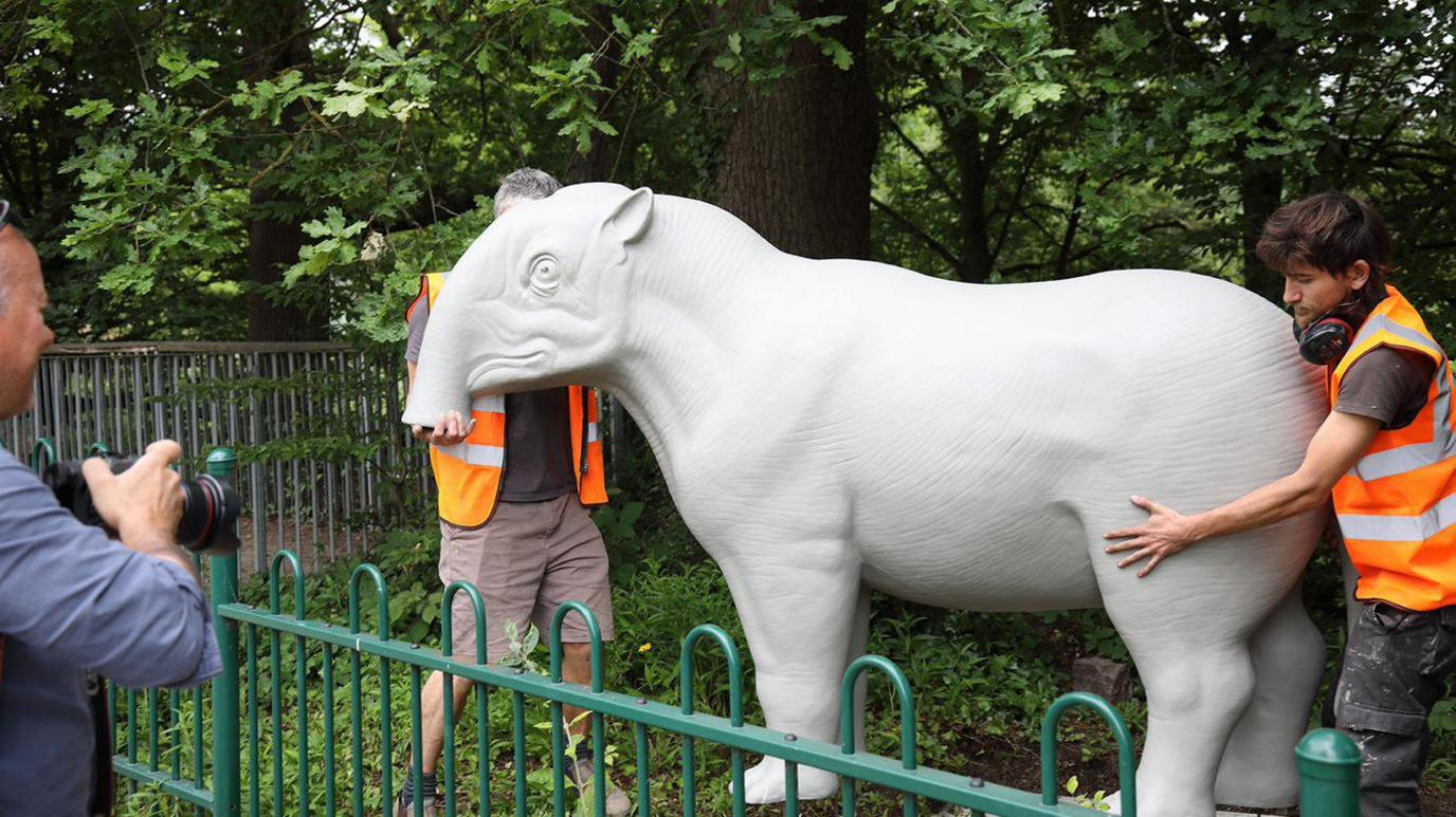 Workmen installing sculpture