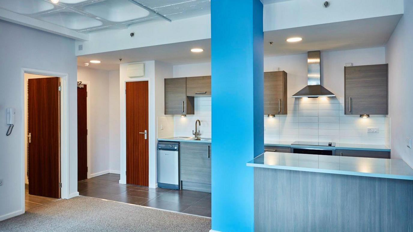 A interior view of one of the flats at Rock House which has a kitchen, countertop and cupboards. 