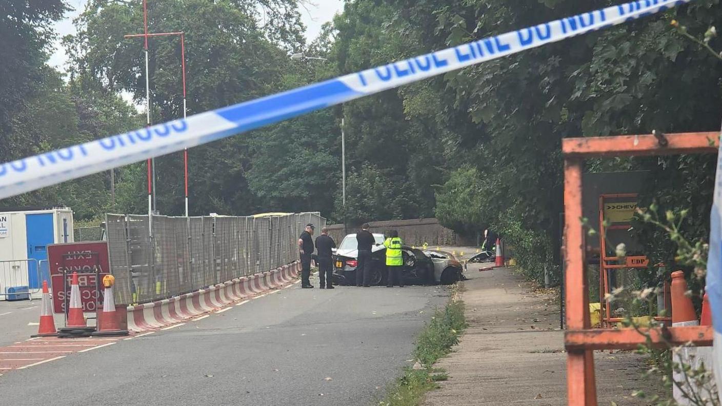 A police car and a crime scene investigation van are parked on a road.
