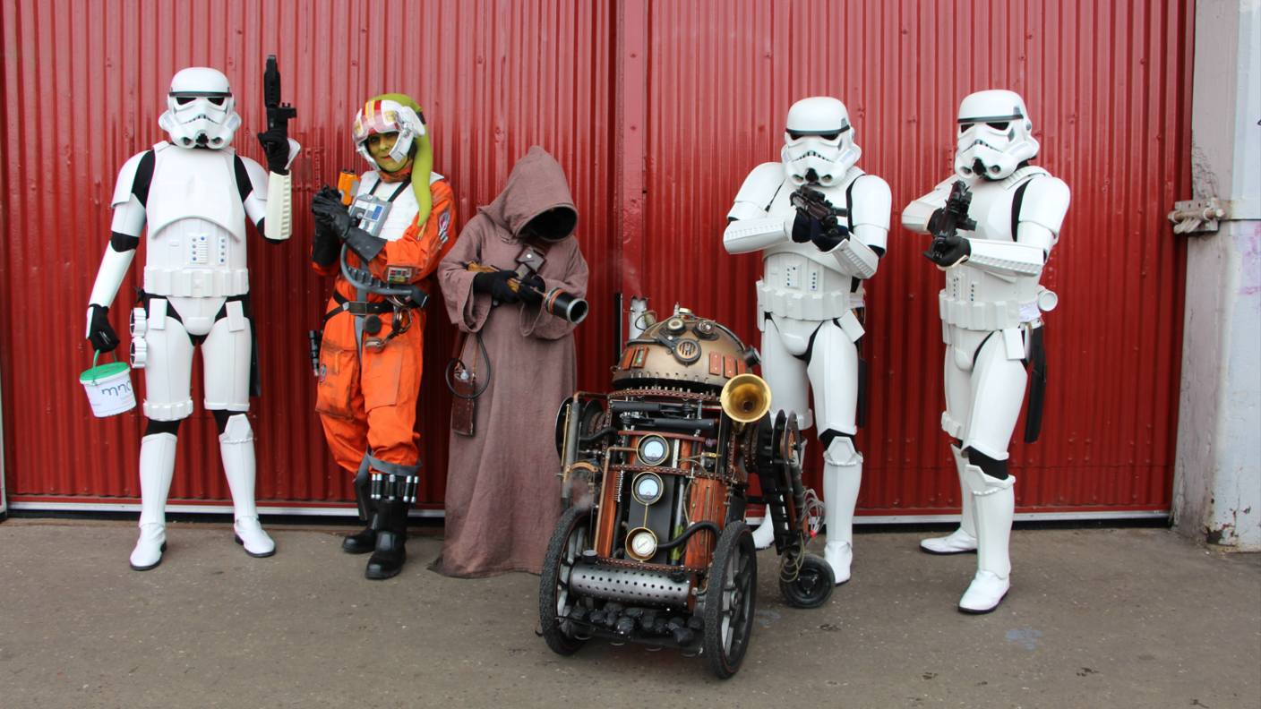 Life-sized props of storm troopers and other sci-fi characters in front of a red gate.