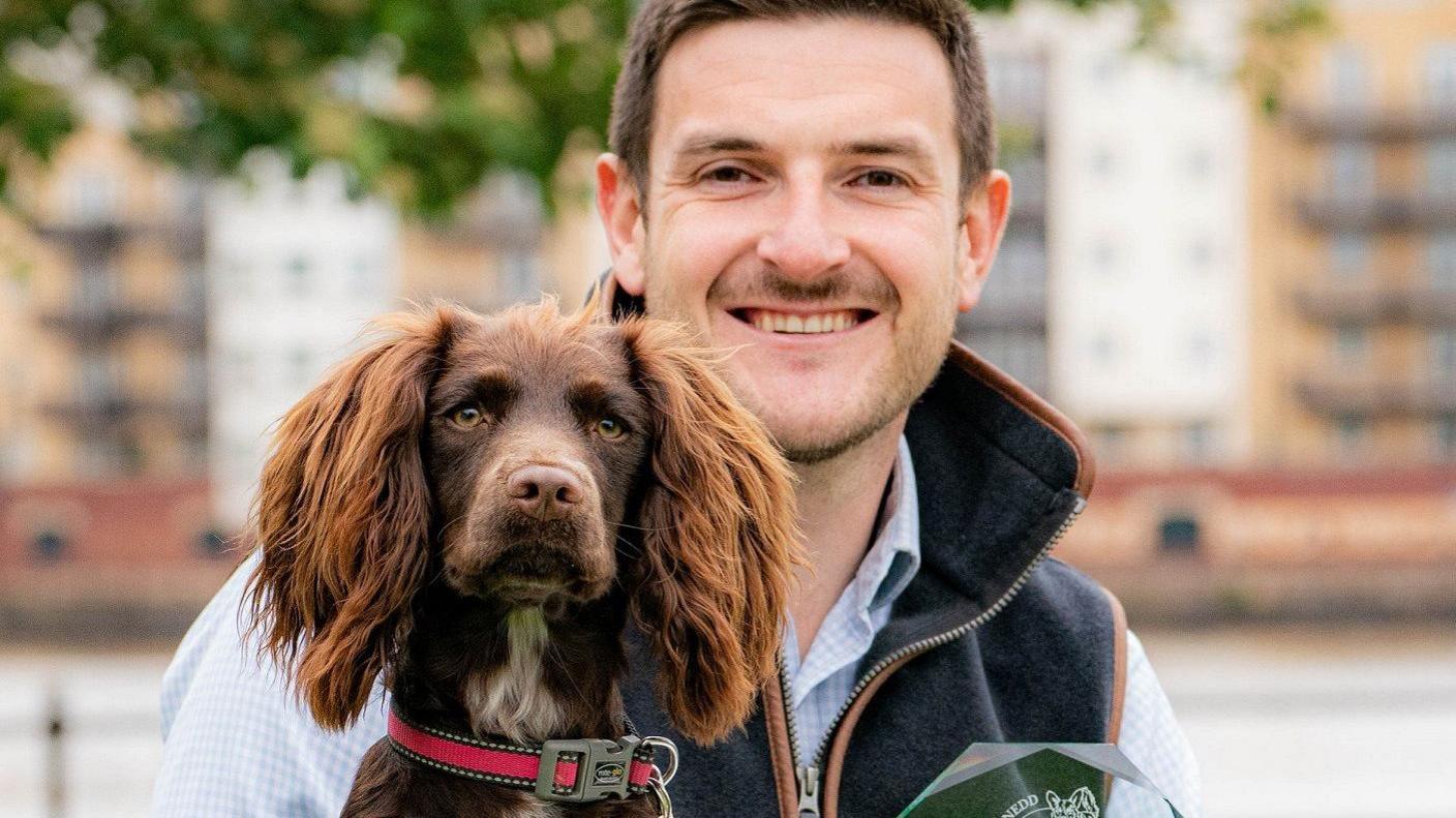 Bonnie, the cocker spaniel who won the public vote, with Conservative Member of the Senedd James Evans