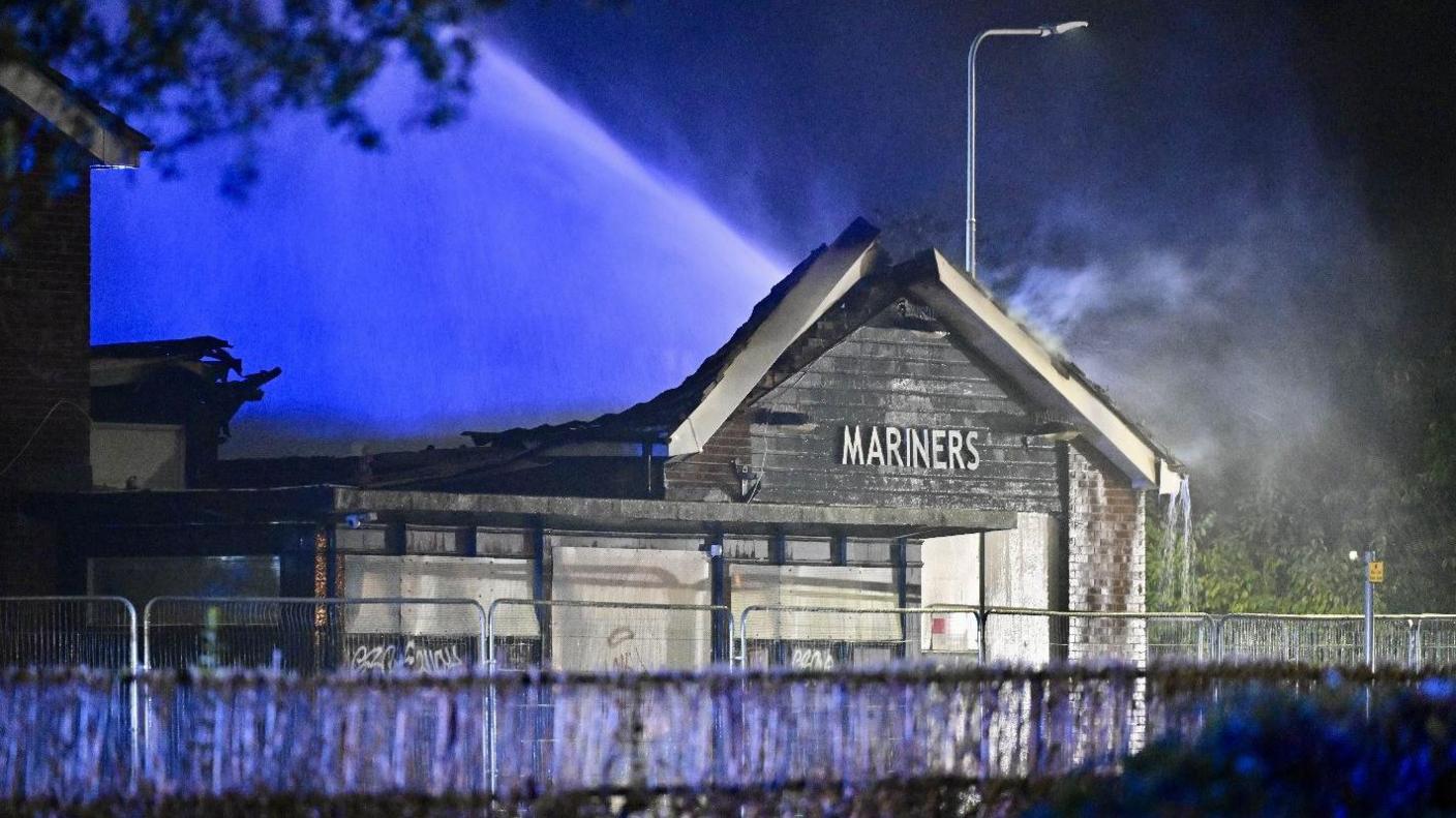 The front of the derelict Mariners Rest pub in Grimsby. Fire damage to the roof is visible as water is sprayed on to it