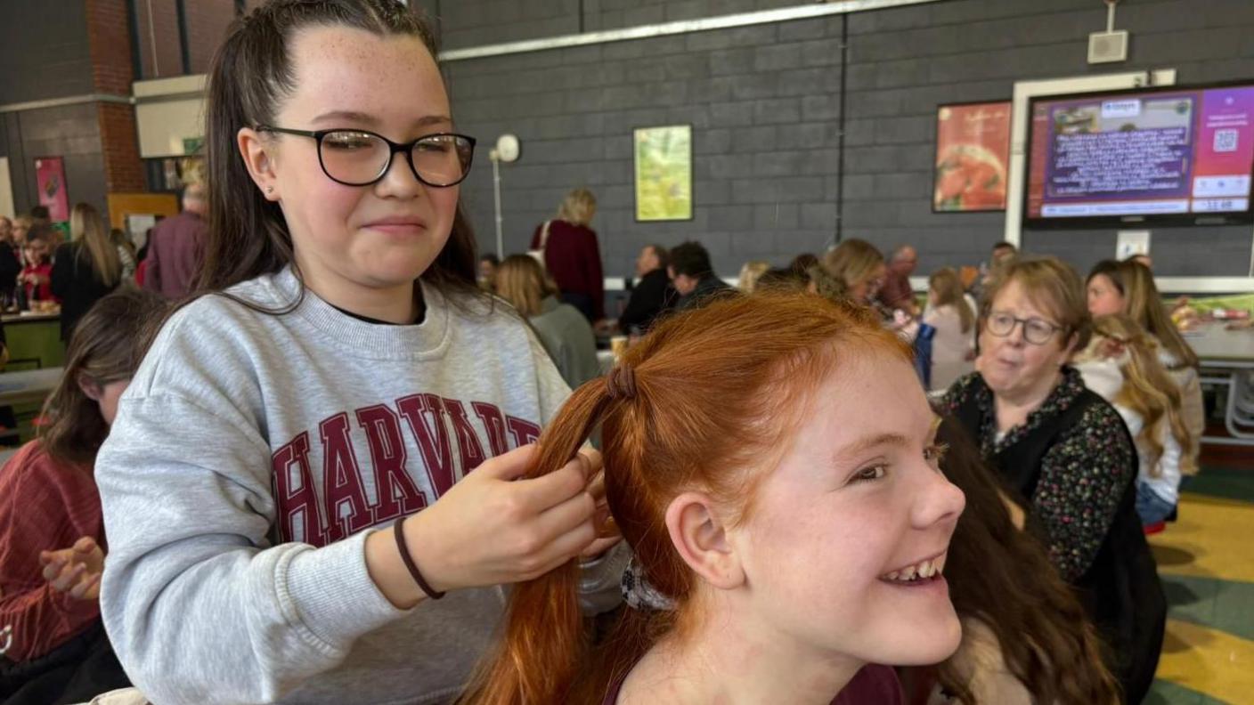 Tara, 11 wrthi yn paratoi gwallt Glain, 14, cyn y grŵp stepio