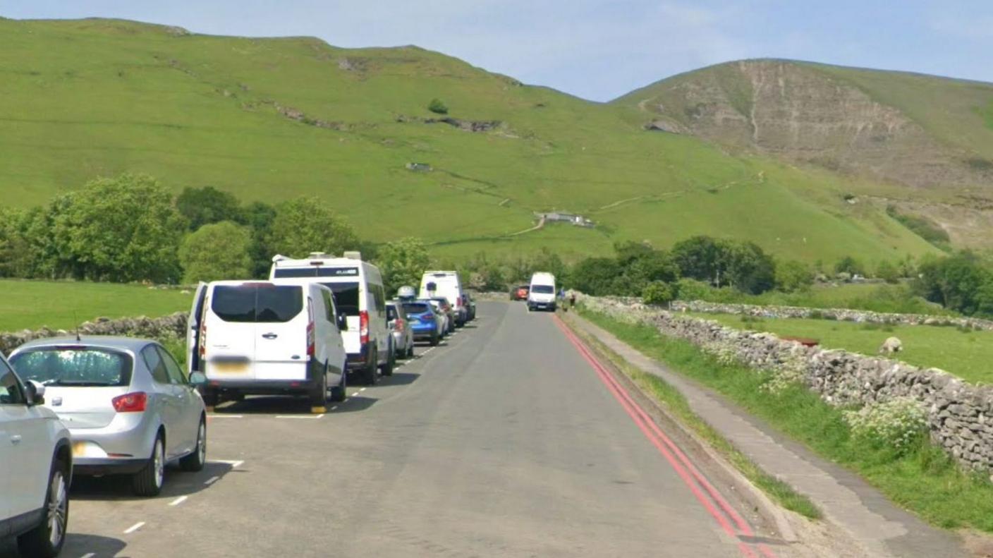 Double red lines on a road with a hill behind the road