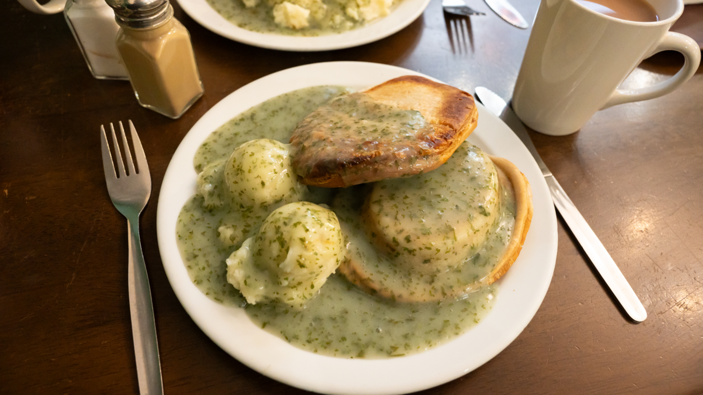 Pie and mash served on a plate smothered in parsley liquor