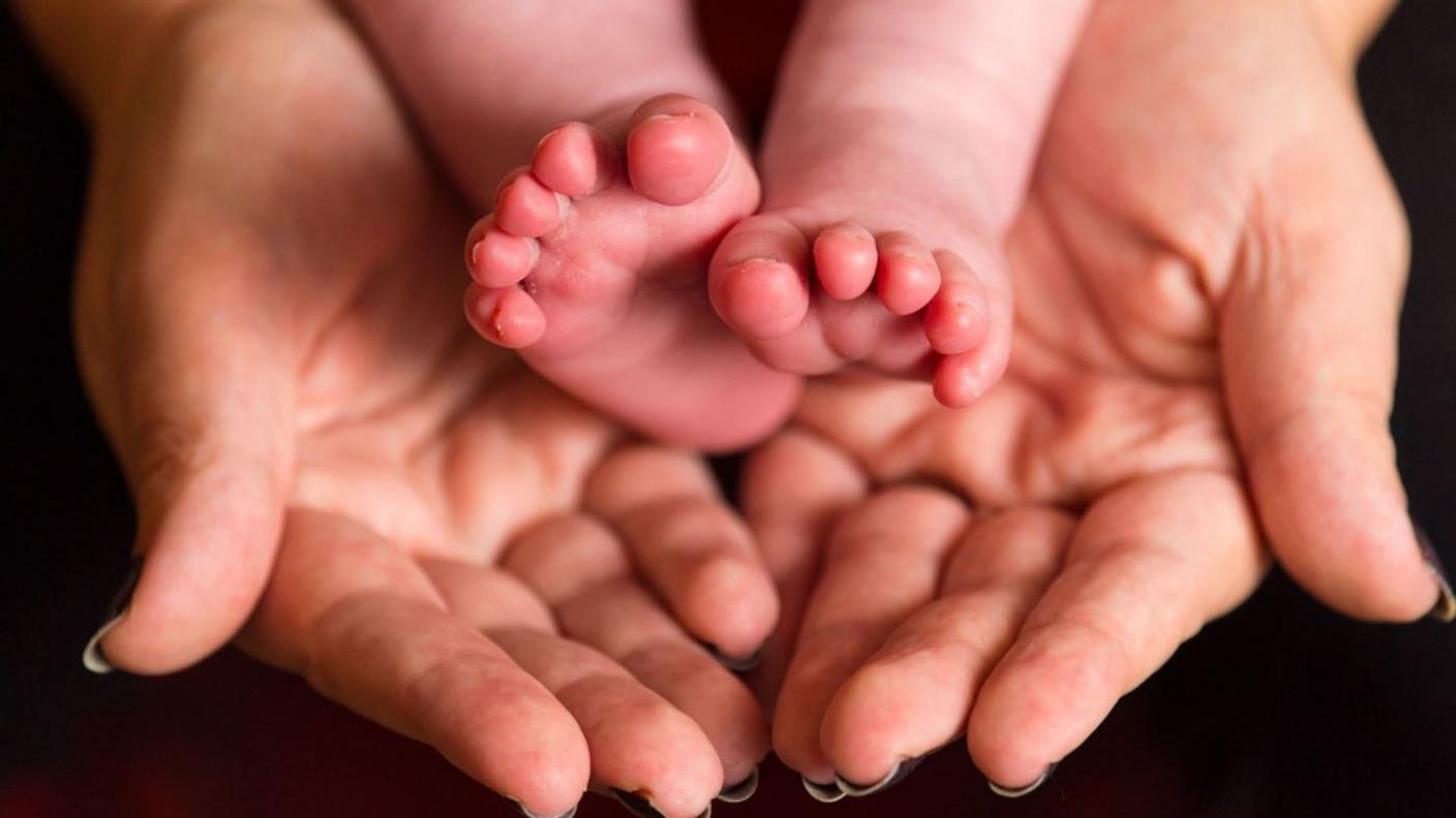 A mother holding the feet of a new baby