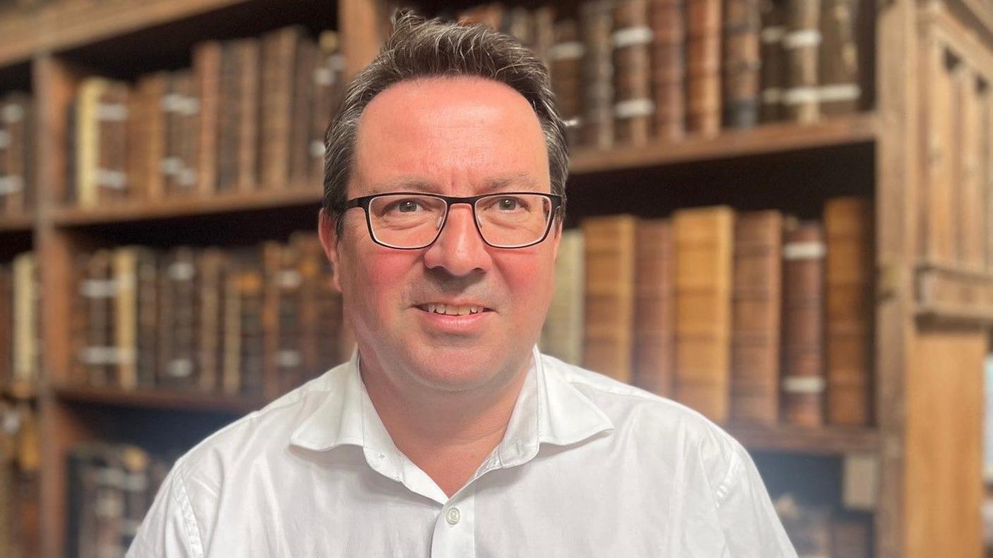 A man stands in a library of antiquarian books