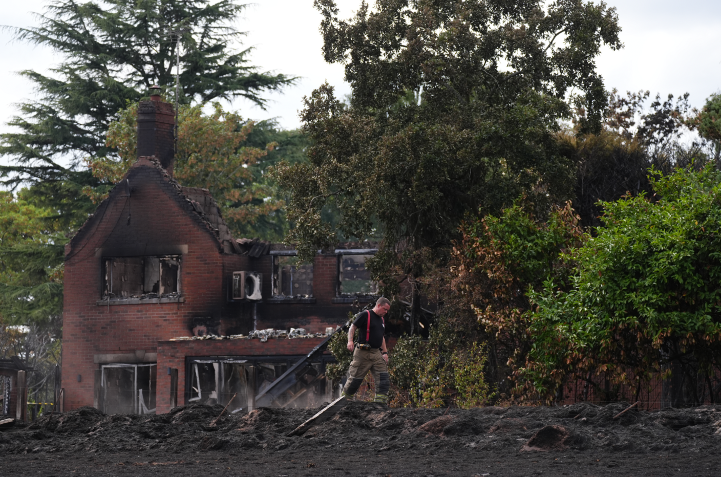 A fireman walks in front of a completely destroyed house 