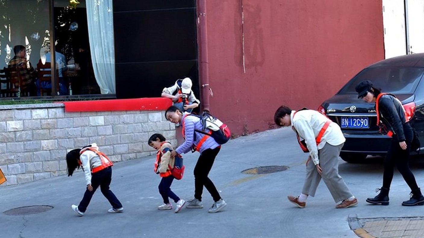 Mr. Deng and several participants crouch to avoid being caught by a surveillance camera.