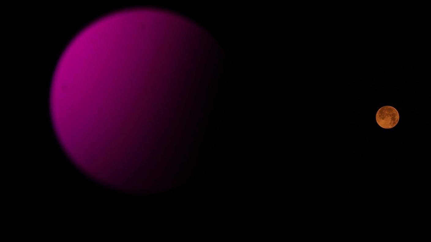 The full moon rises over colourful street lights in New Delhi, India,