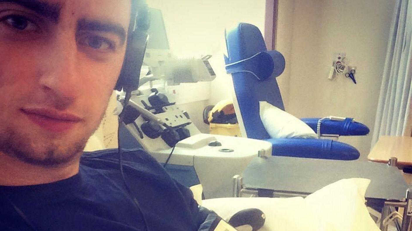 A close-up selfie of Mr Green who sits in a hospital chair looking into the camera. Equipment and another chair can be seen in the background.