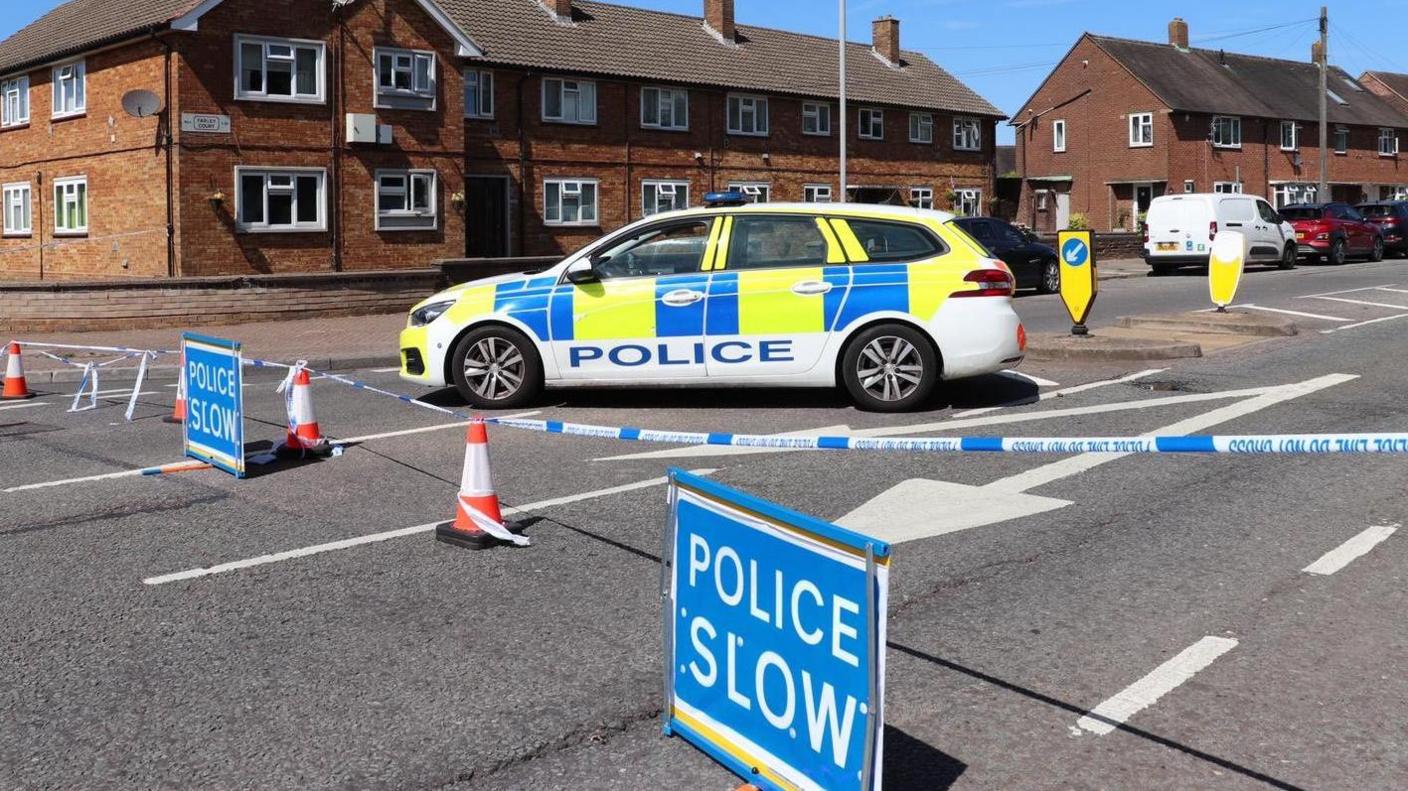 A Bedfordshire police car, in Luton, with Police slow signs and police tape