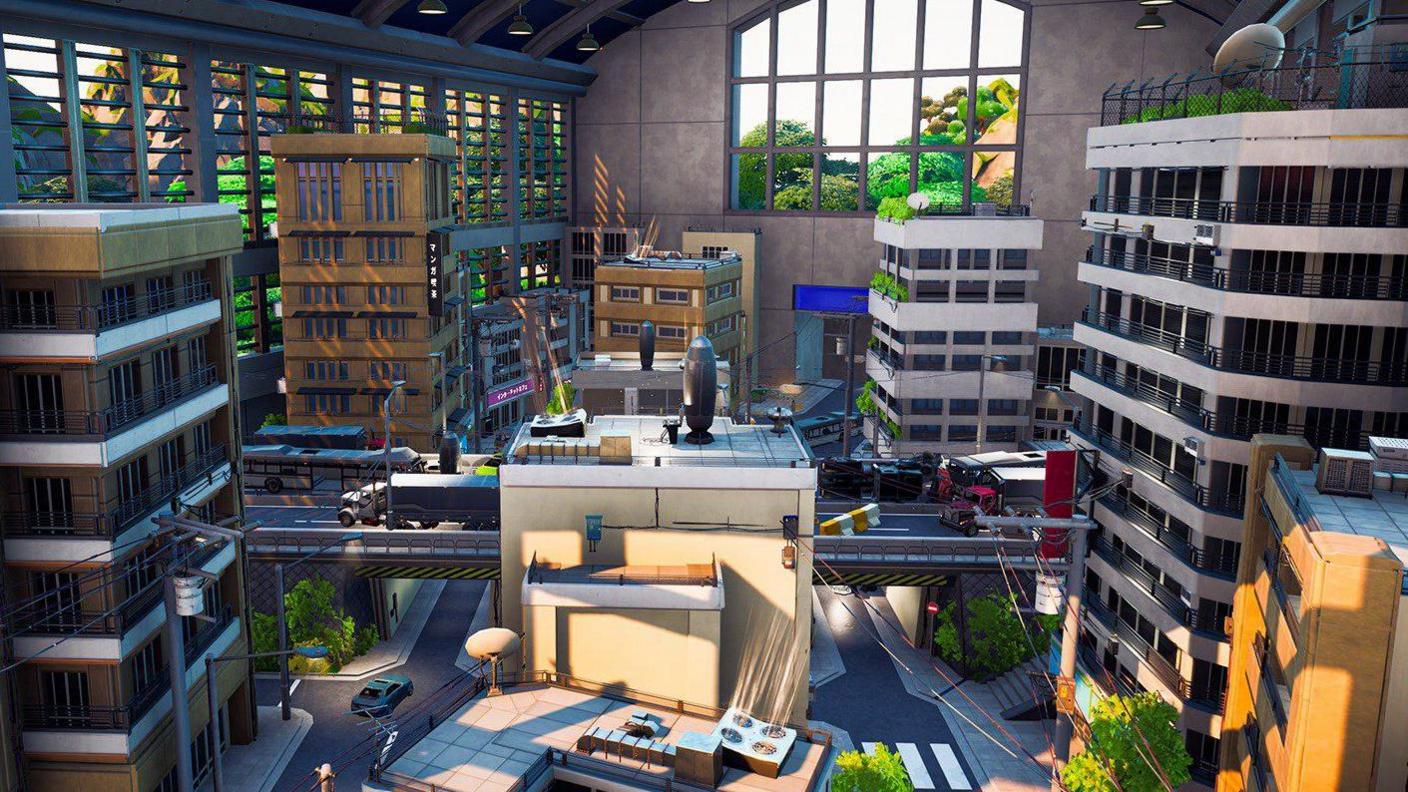 A screenshot showing an aerial view of a city scene from Fornite's level editor. Several tall office buildings overlook an intersection. The city scene itself appears to be housed inside a giant garage.