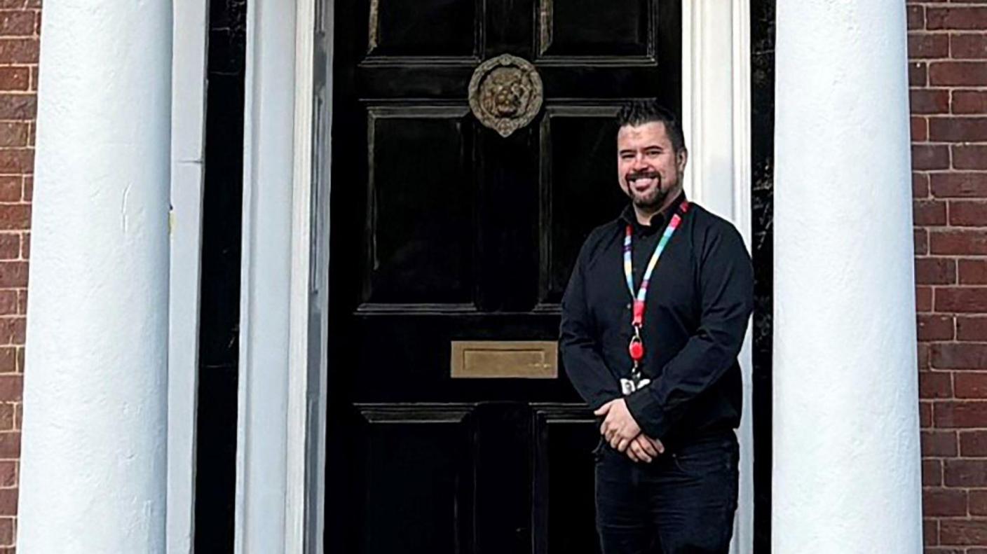 Robert stands outside the school door