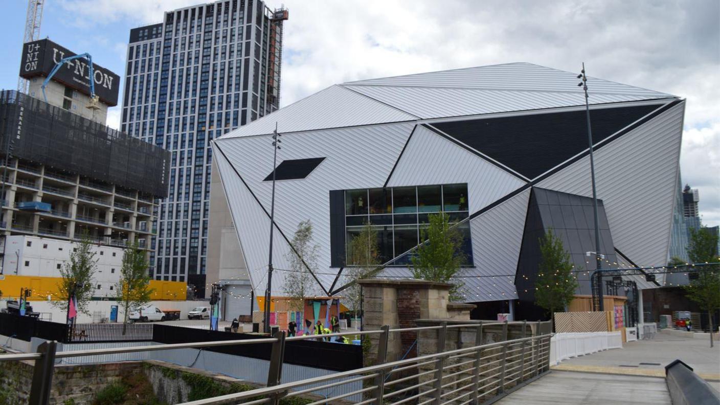 A view of the Aviva Studio building in Manchester from a nearby bridge