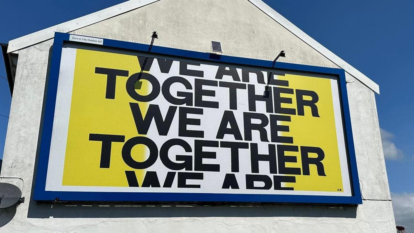 A colourful mural on the side of the building, saying "WE ARE TOGTHER WE ARE TOGETHER"