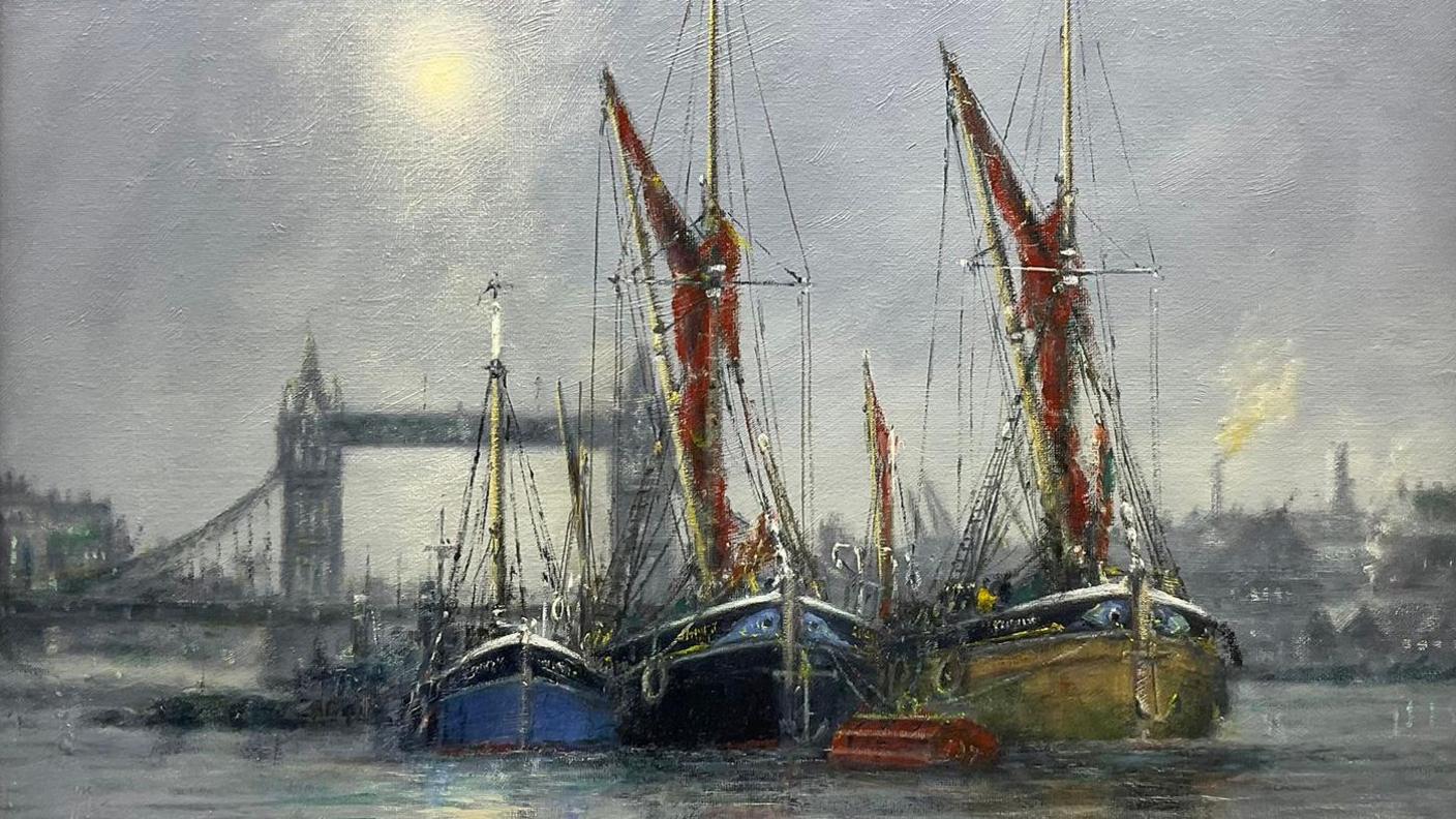 A painting by Jack Rigg shows three small, traditional sailing boats, two with red sails, moored side-by-side in the River Thames. In the background is Tower Bridge and the London skyline, lit by moonlight.