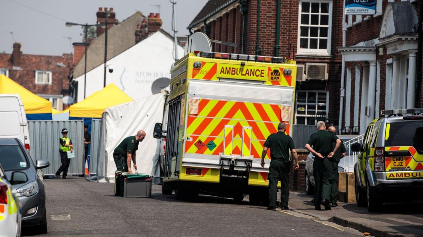 Emergency services outside John Baker House Sanctuary Supported Living in July 6, 2018 in Salisbury, England. An ambulance sits on the road and there are several white incident tents outside the property.