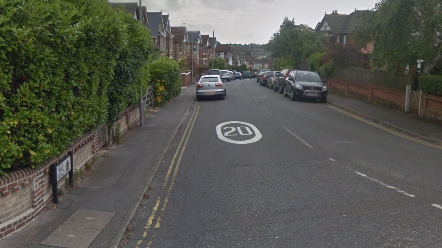 Vale Road, a residential street with detached houses on either side and cars parked on both sides of the road