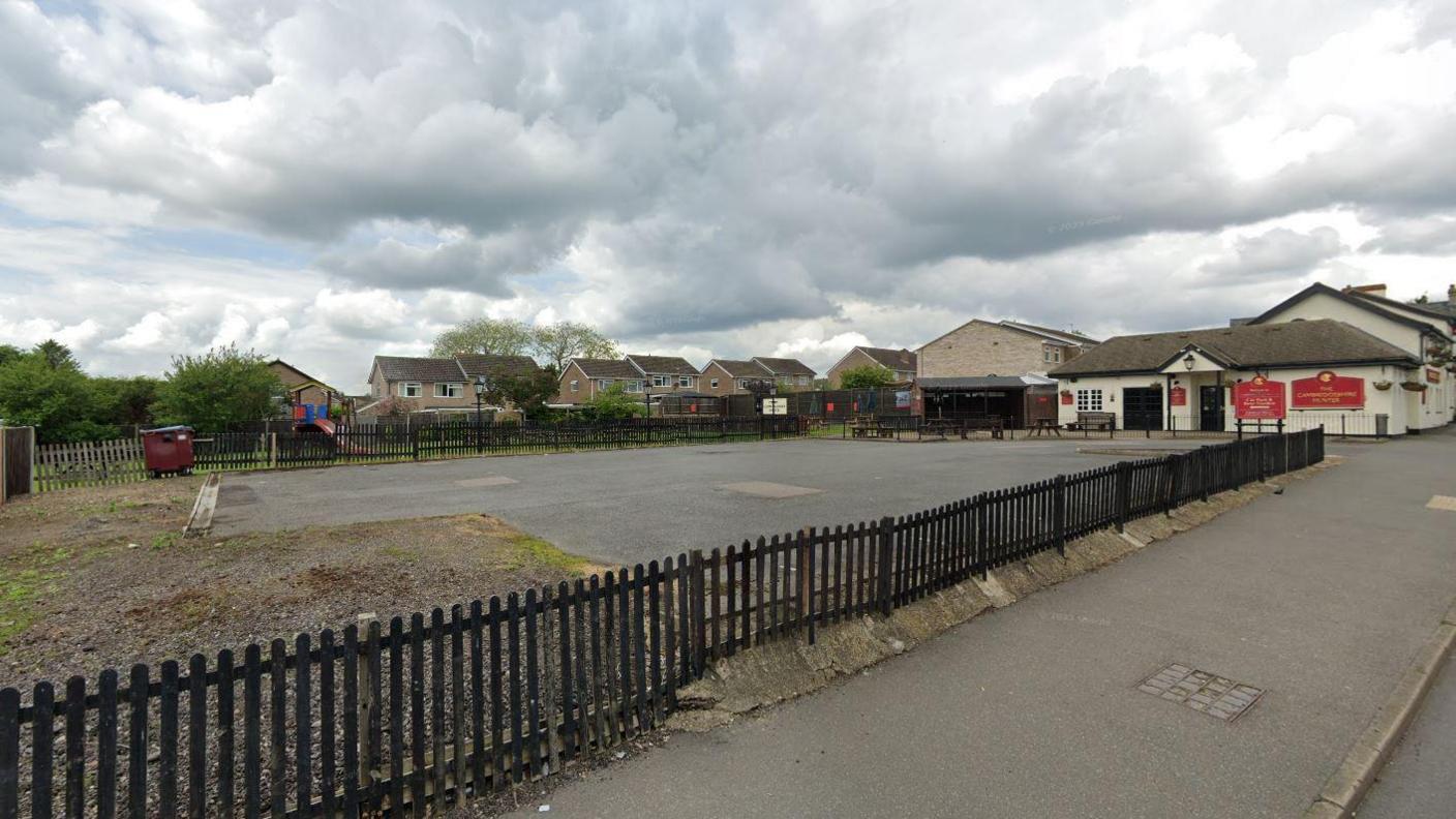 Car park next to The Cambridgeshire Hunter pub, view from street, rows of houses in the background