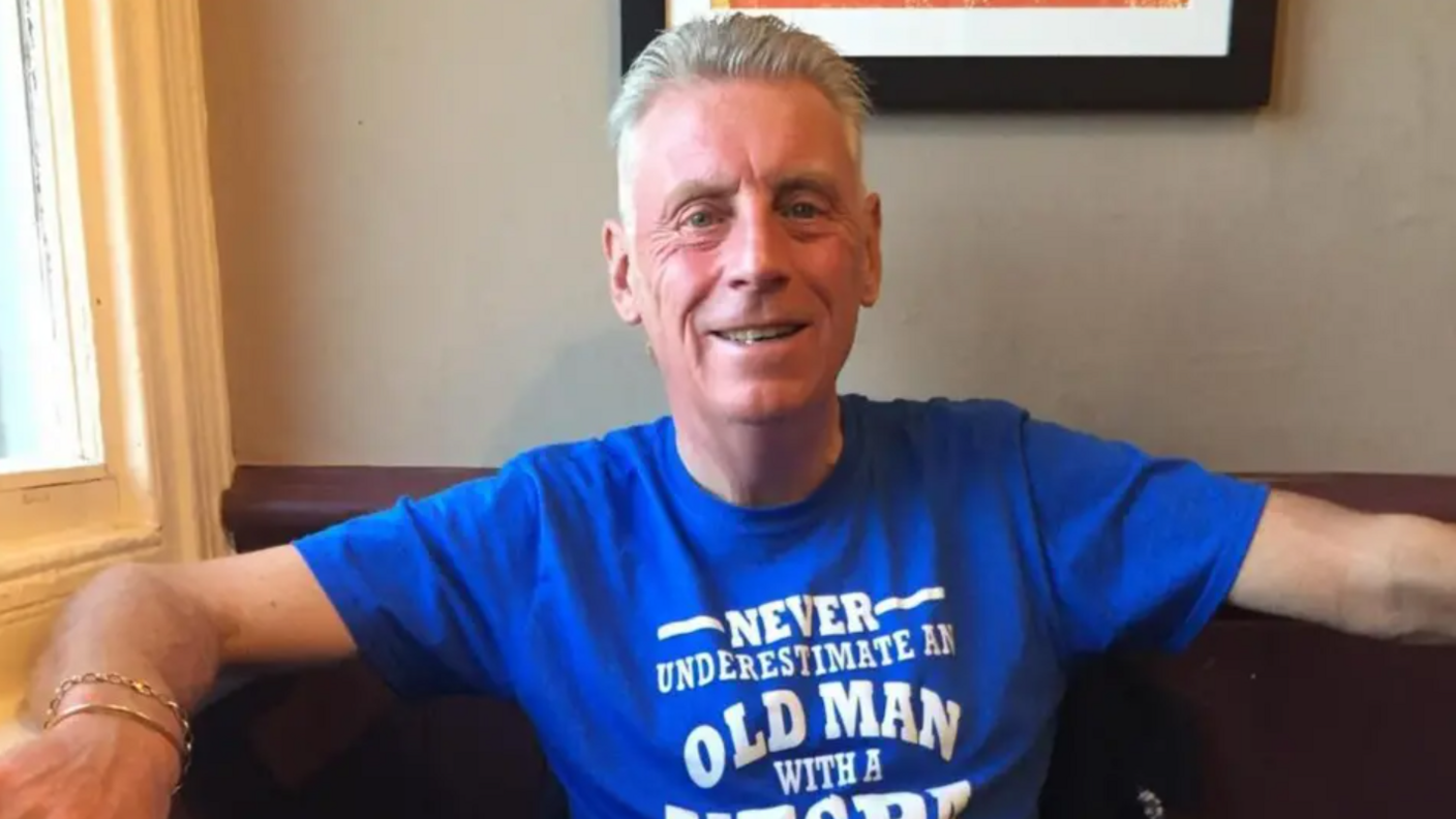 A man with short grey hair wearing a blue t-shirt