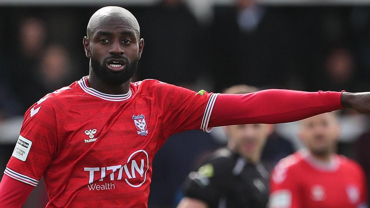 Hiram Boateng in action for York City with his left arm raised and pointing