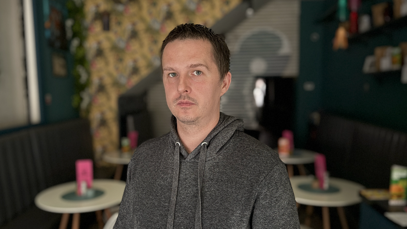 James Usher; a man wearing a grey, hooded top stands inside a cafe without any power