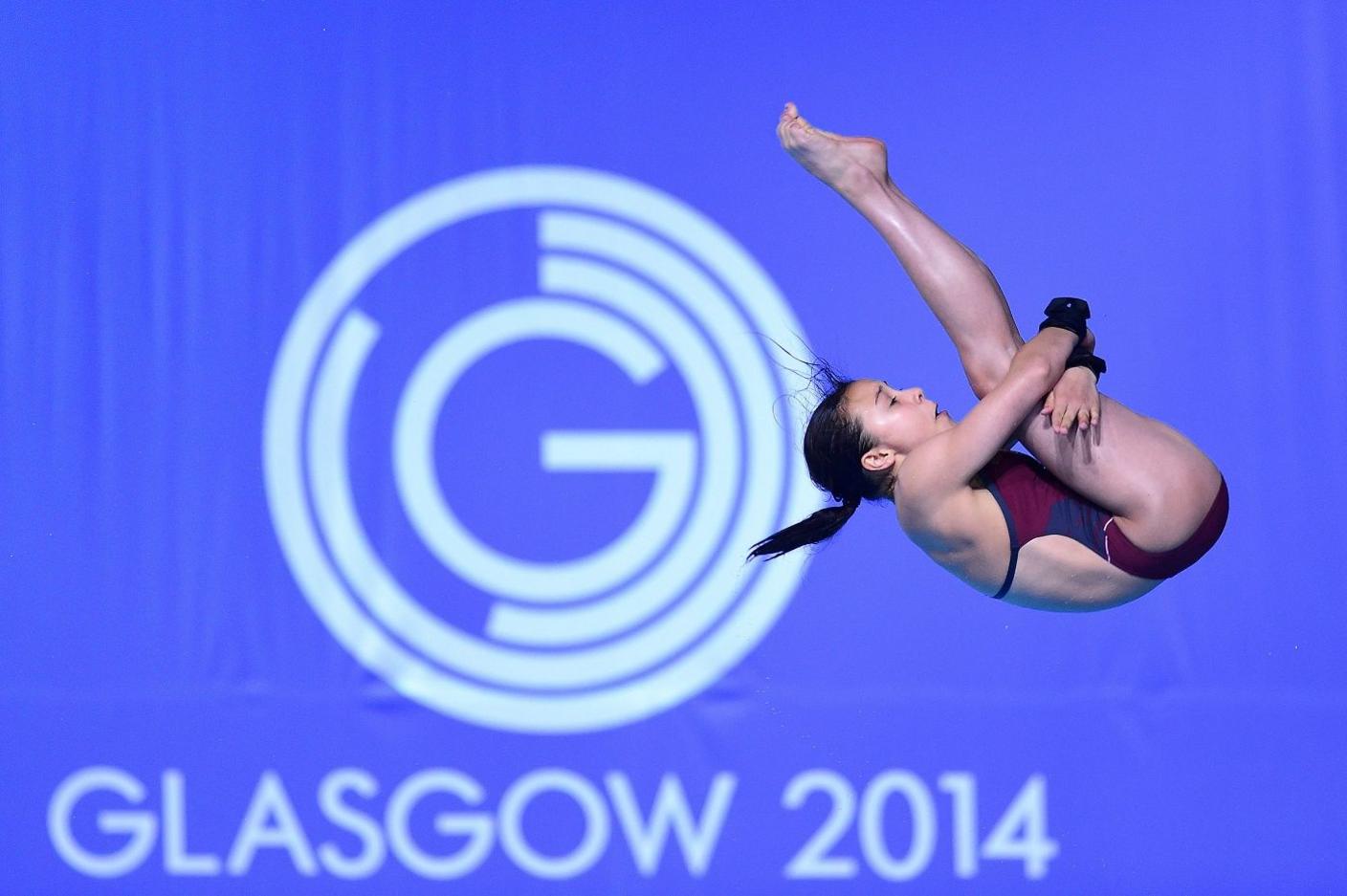 Diver in the air in front of 2014 Glasgow Commonwealth Games logo. 