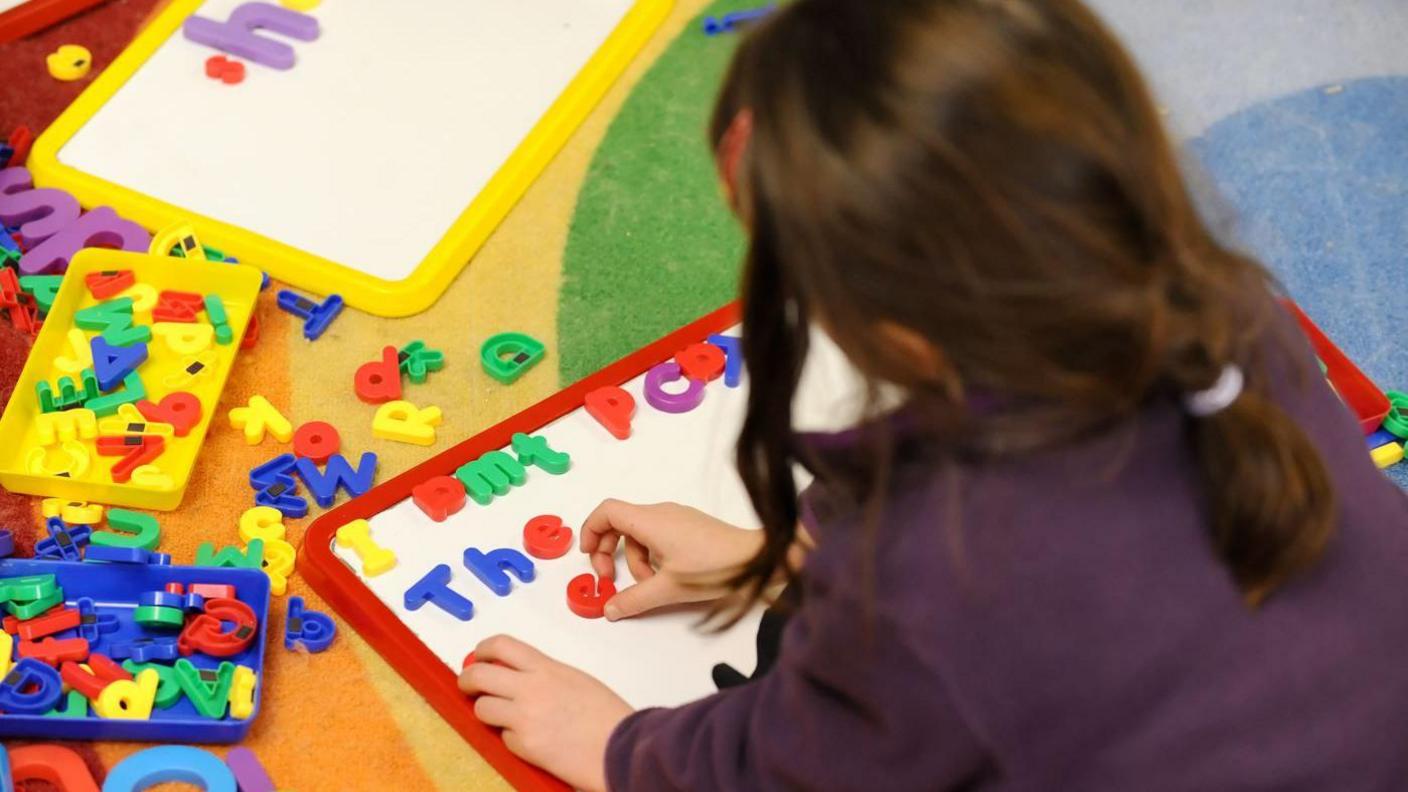 A child playing with magnetic letters on a whiteboard