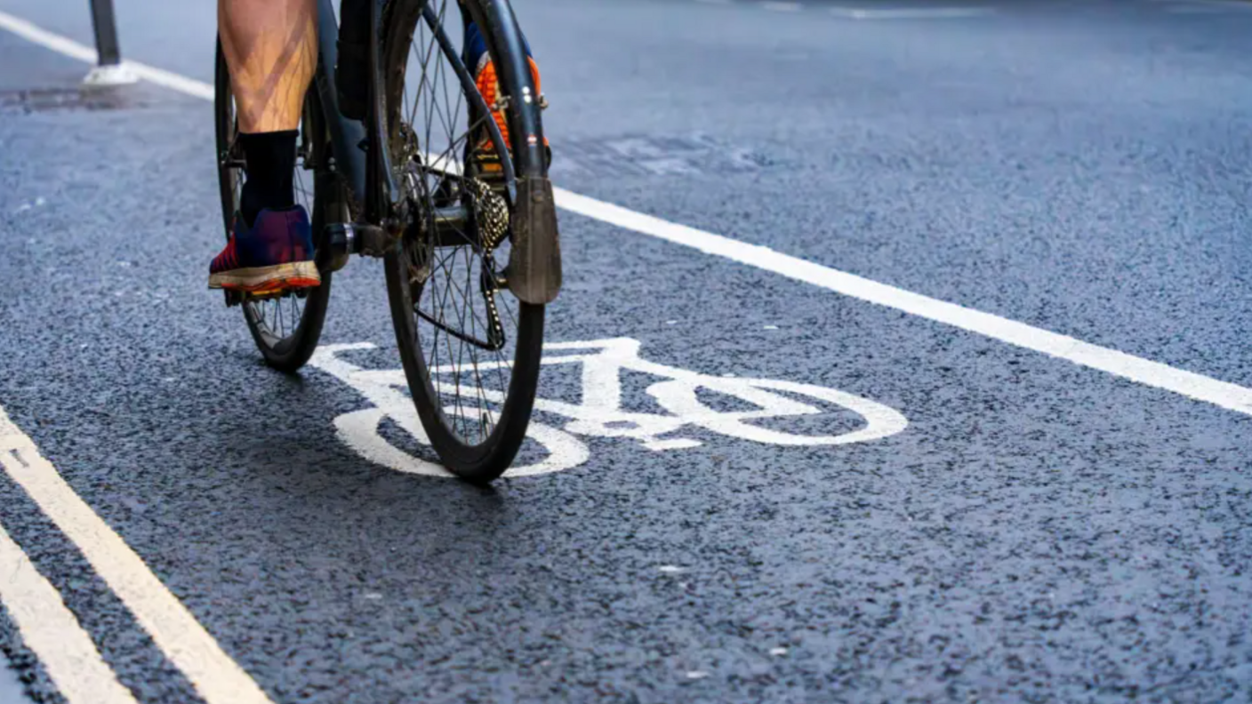 Someone riding a black bike in a cycle lane.