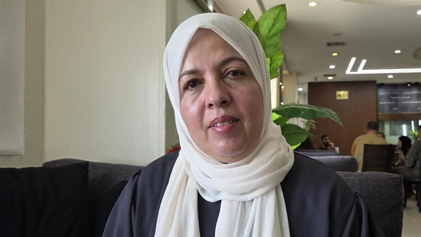 Palestinian woman wearing a white hijab looks at the camera