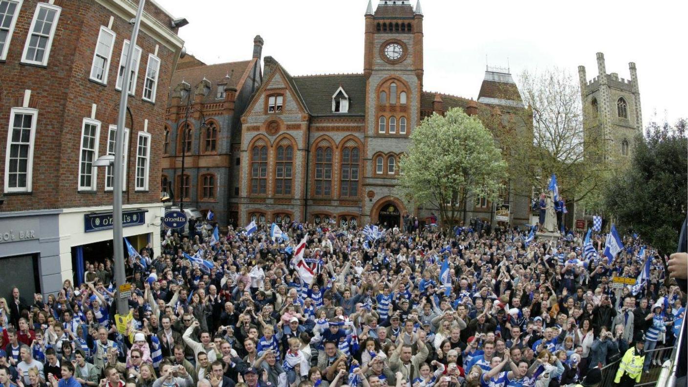 A large group of Reading supporters stood in front of the grey and orange town hall.