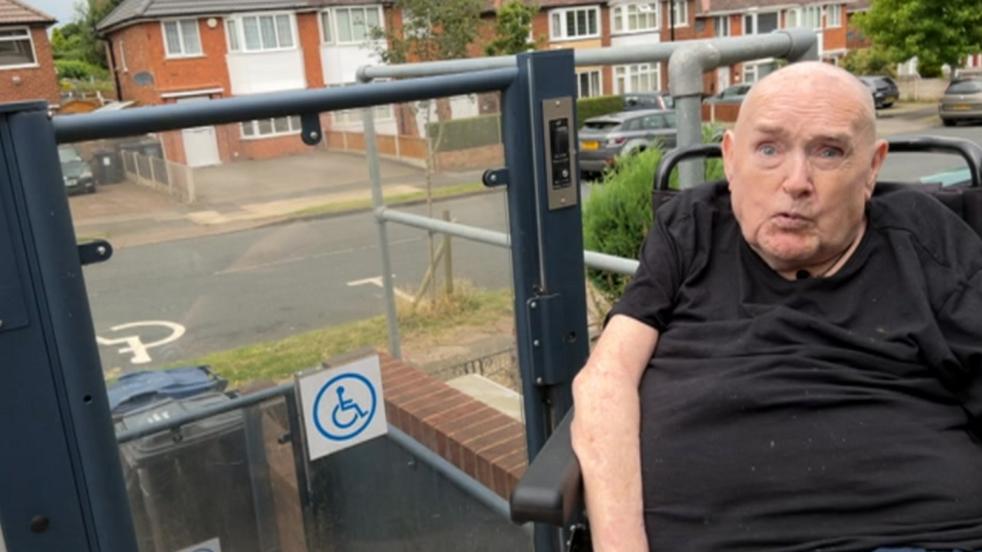 A man in a wheelchair next to a lift outside a property