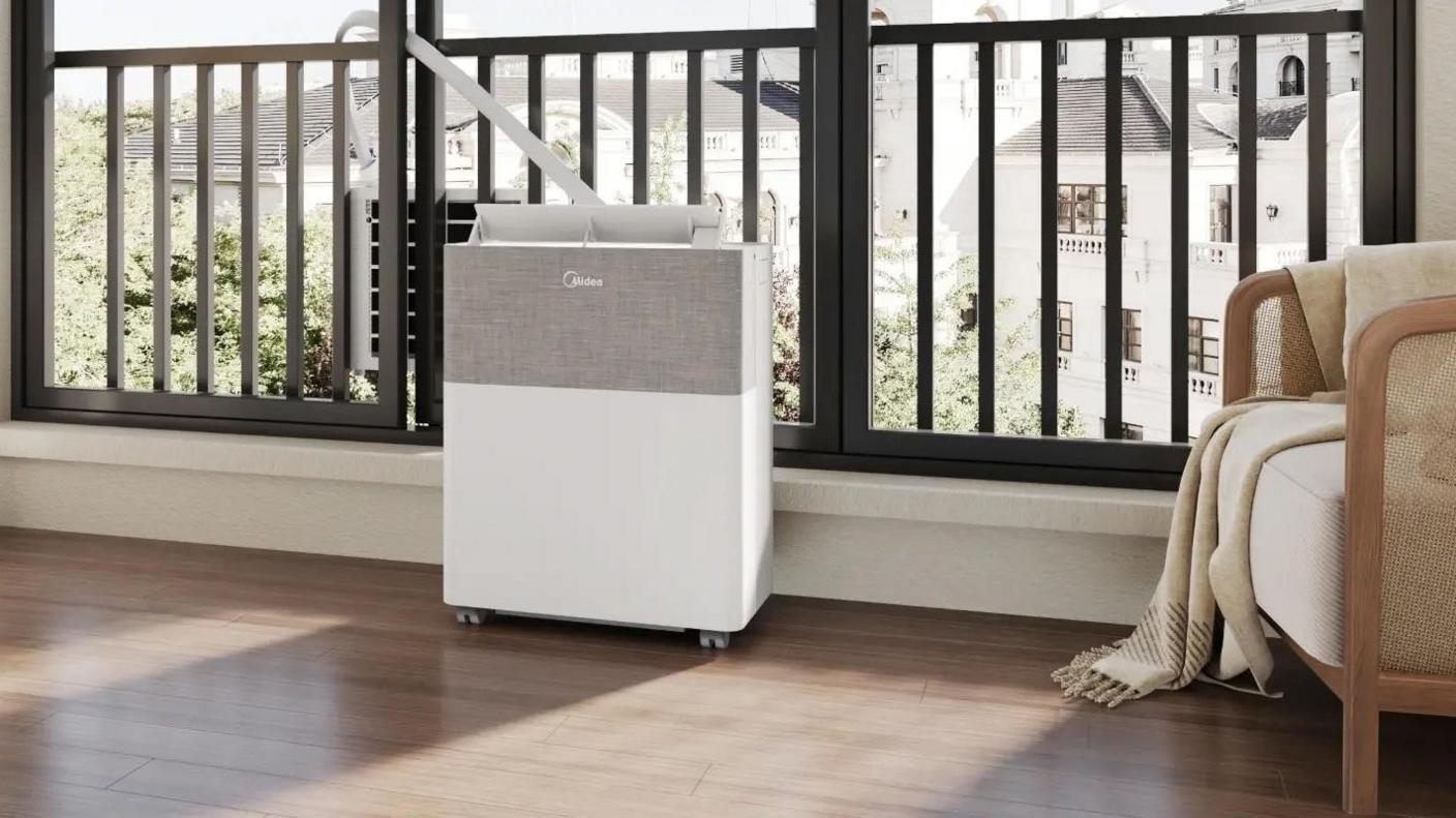 A Midea PortaSplit by the window of an apartment, with a tube connecting the indoor and outdoor units