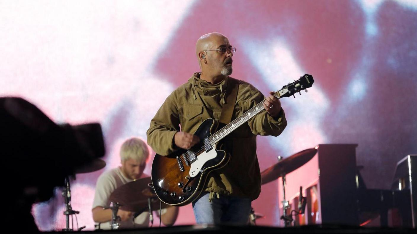 Bonehead performing on stage with Oasis 
