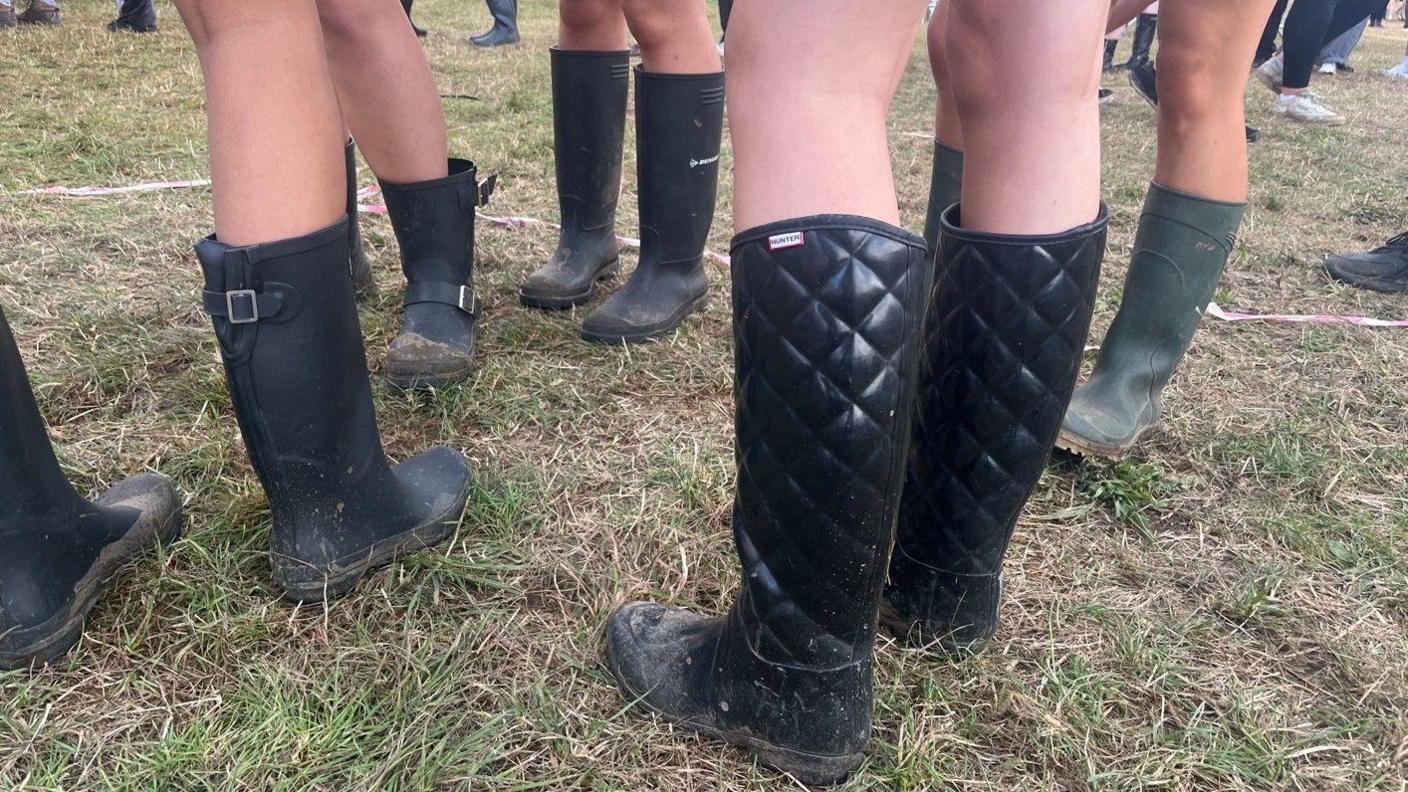 The feet of a group of people all wearing black or dark green wellies