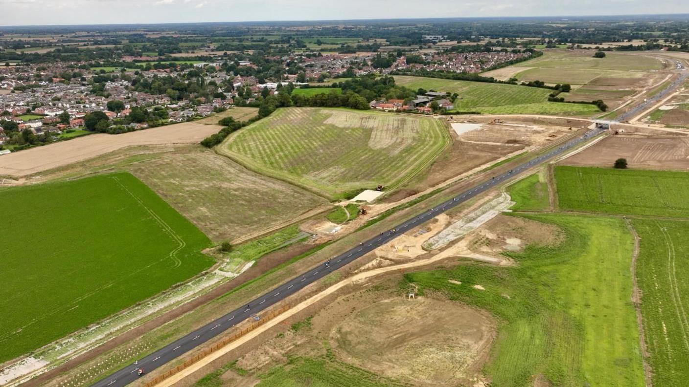 An aerial view of the new bypass, surrounded by fields with a town visible in the background.