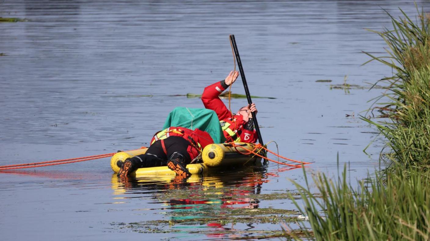 Two search and rescue members scouring the water on a small boat