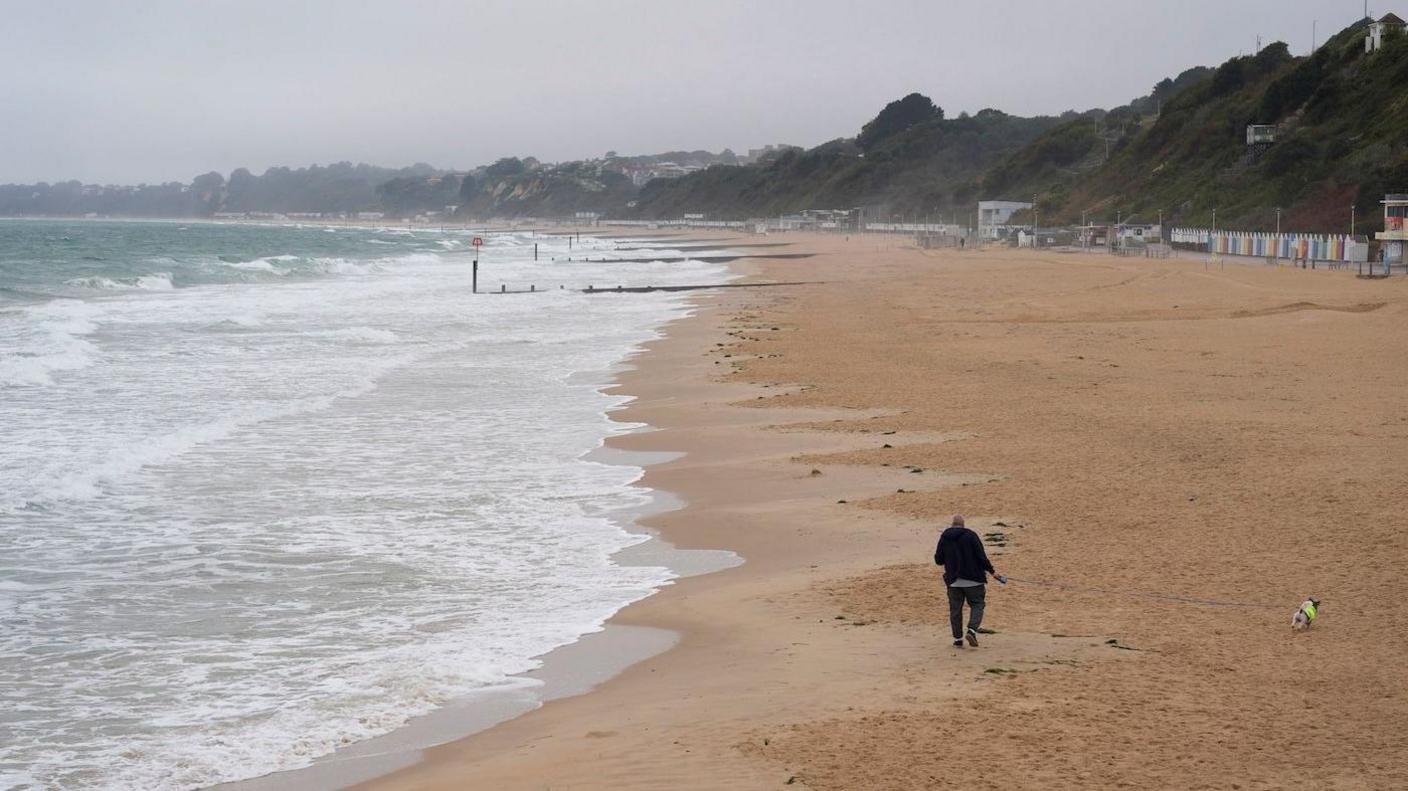 A person walks their dog along Bournemouth Beach in Dorset. 
