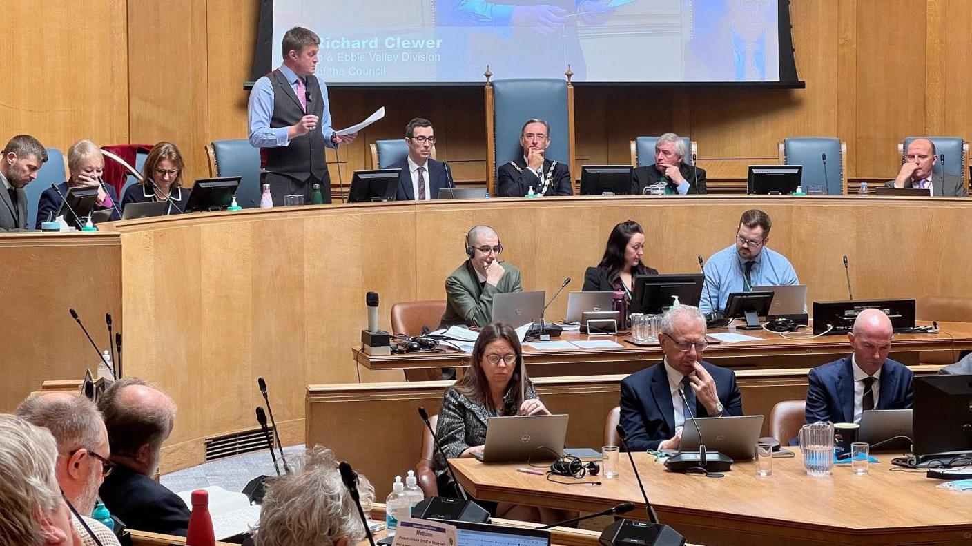 Richard Clewer standing up addressing the council chamber