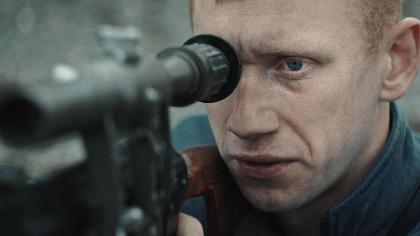 A still of the film shows a distressed Oleksandr Rudynskyy looking down the sights of a rifle gun