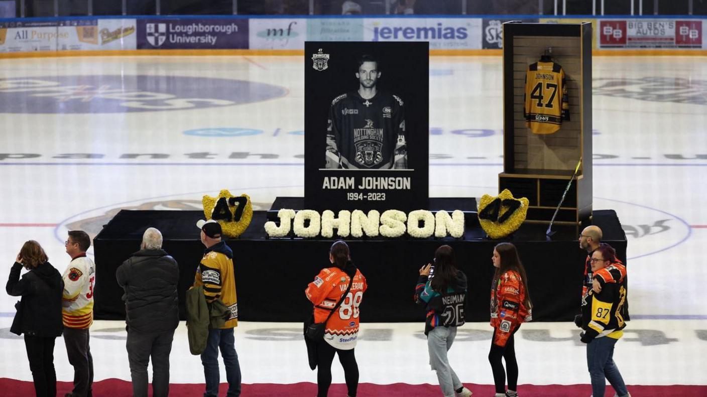 Fans walk past a memorial of Adam Johnson on the ice in Nottingham