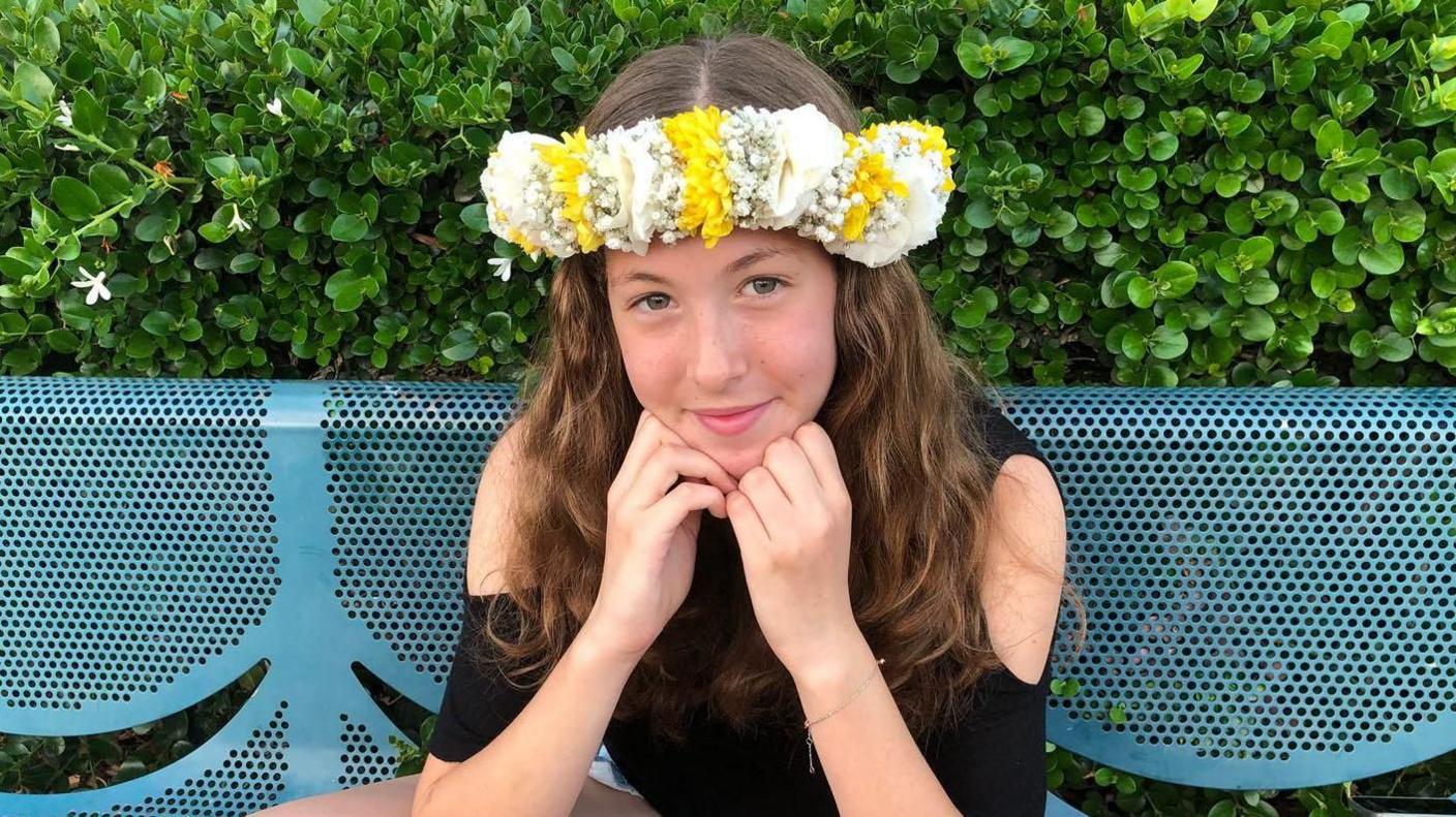 Naama Levy smiles to camera with her hands under her chin