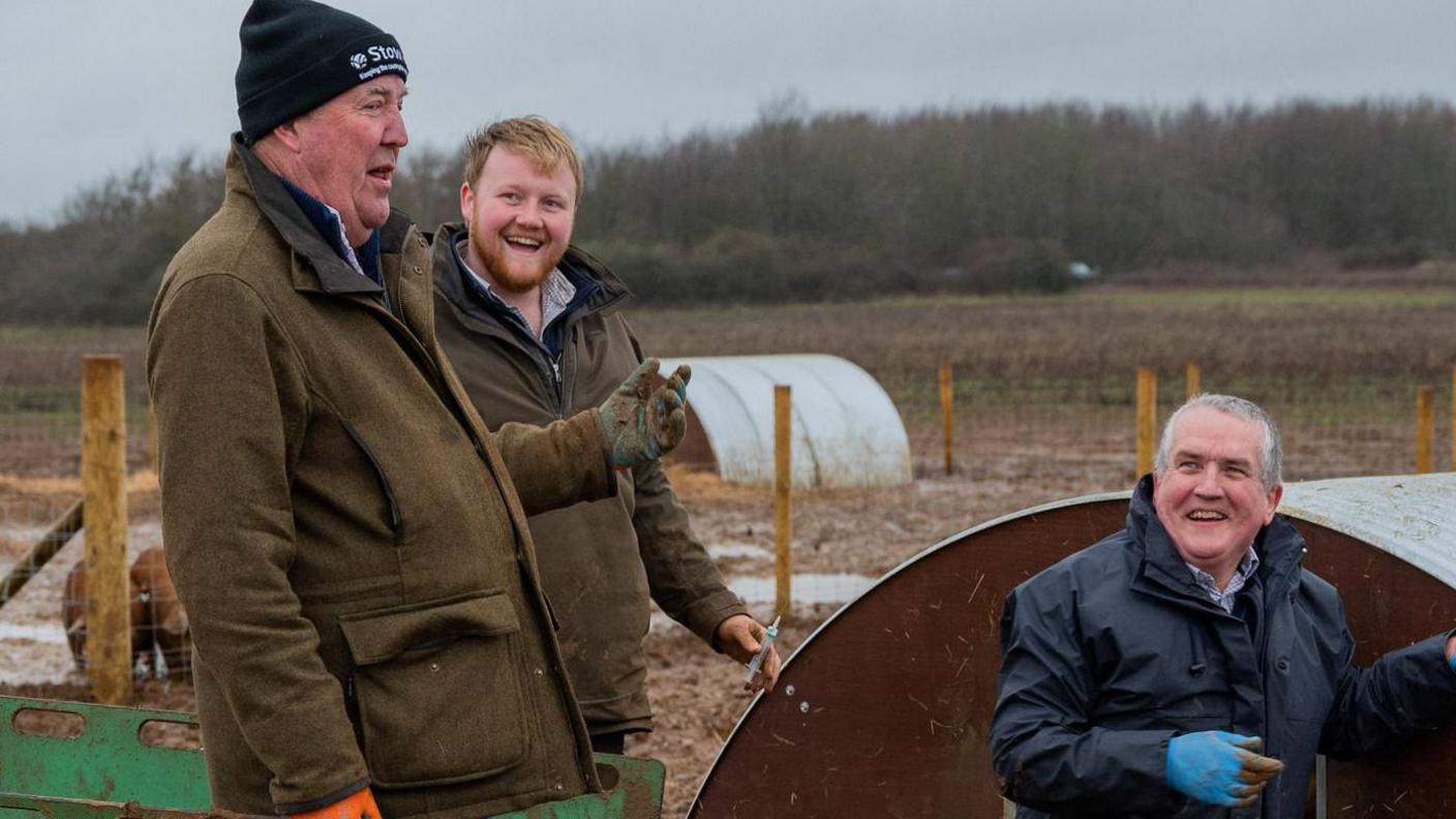 Jeremy Clarkson, farm manager Kaleb Cooper and vet Dilwyn Evans all smiling near pig pens on Clarkson's farm 